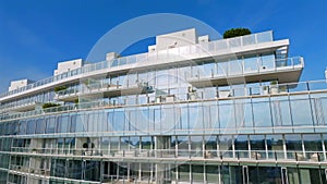 Aerial view of exquisite design of high-raised house with glass facade. Penthouses atop building offering breathtaking