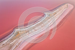 Aerial view of extremely salty lake with salt shelf in the pink water, natural abstract background