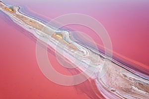 Aerial view of extremely salty lake with salt shelf in the pink water, natural abstract background