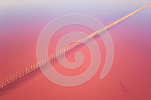 Aerial view of extremely salty lake with wooden logs for salt extraction in the pink water, natural abstract background