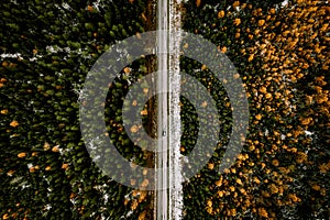 Aerial view of fall road with autumn woods and first snow in Finland