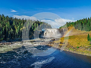 Aerial view famous waterfall Tannforsen northern Sweden, with a rainbow in the mist and rapid flowing cascades of water