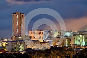 Aerial view of fancy hotels and apartment buildings lit up brighly in Sea Point, Cape Town, South Africa at night. An