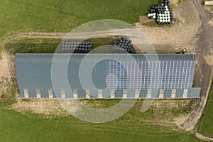 Aerial view of farm building with photovoltaic solar panels mounted on rooftop for producing clean ecological