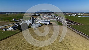 Aerial View Of A Farm Complex With Multiple Barns, Silos, And Plowed Fields In A Rural Setting