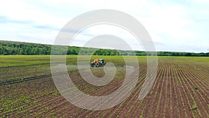 Aerial view Farm machinery spraying insecticide to the green field, agricultural natural seasonal spring works. Farming