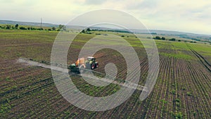 Aerial view Farm machinery spraying insecticide to the green field, agricultural natural seasonal spring works. Farming