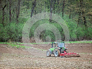 Farm tractor harrowing arable field photo