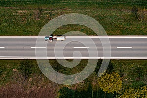 Aerial view of farm tractor hauling fecal tank on country road, drone pov