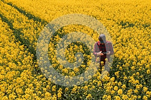 Aerial view of farmer with drone remote controller in rapeseed field using innovative technology