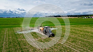 Aerial view, Farmer on a tractor with a sprayer makes fertilizer for young vegetables