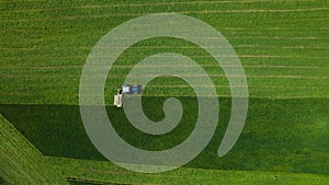 Aerial view of farming tractor mowing green field.
