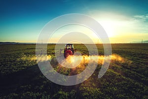 Aerial view of farming tractor plowing and spraying on field