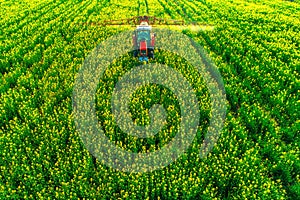 Aerial view of farming tractor plowing and spraying on field