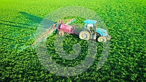 Aerial view of farming tractor plowing and spraying on field