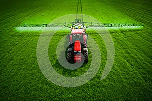 Aerial view of farming tractor plowing and spraying on field