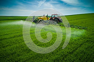 Aerial view of farming tractor plowing and spraying on field