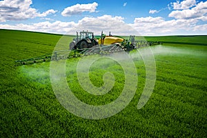 Aerial view of farming tractor plowing and spraying on field