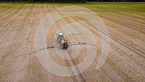 Aerial view of farming tractor plowing and spraying on field