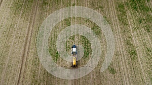 Aerial view of farming tractor plowing and spraying on field