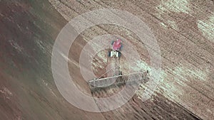 Aerial view of farming tractor plowing and spraying on field