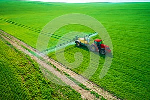 Aerial view of farming tractor plowing and spraying on field