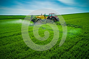 Aerial view of farming tractor plowing and spraying on field