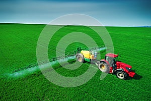 Aerial view of farming tractor plowing and spraying on field