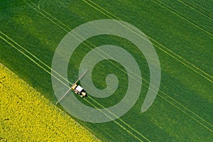 Aerial view of farming tractor plowing and spraying on field.  Agriculture. View from above. Photo captured with drone