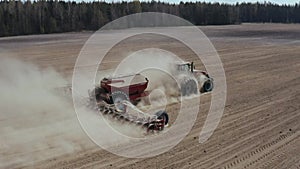 Aerial view of farming tractor seeding agricultural crops at field. Farm machinery sowing crops at field. Agricultural
