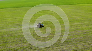 Aerial view of farming tractor spraying with chemicals on field