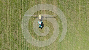 Aerial view of farming tractor spraying on field with sprayer, herbicides and pesticides at sunset. Farm machinery