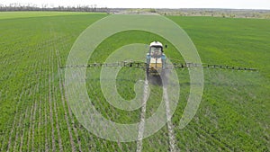 Aerial view of farming tractor spraying on field with sprayer, herbicides and pesticides at sunset. Farm machinery