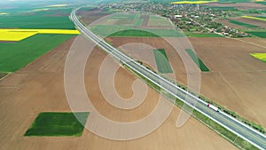 Aerial view of farmland, rapeseed and wheat fields, and highway road in the countryside