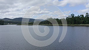 Aerial view, fast drone flying low over the river water with green trees on the shore, beautiful natural landscape