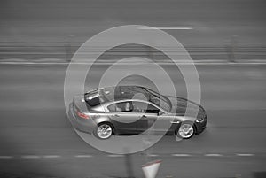 Aerial view of fast moving shiny gray car on the road. speeding in the city concept. desaturated colours and red brake lights