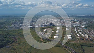 Aerial view of field with trees near the industrial area located outside the city. Clip. Amazing view of factories tanks