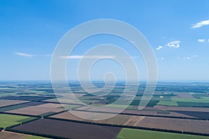 Aerial view of fields with various types of agriculture, against blue sky