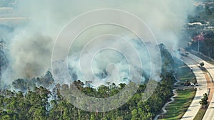 Aerial view of fire department firetrucks extinguishing wildfire burning severely in Florida jungle woods. Emergency