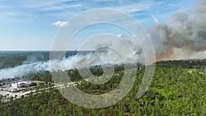 Aerial view of fire department helicopter extinguishing wildfire burning severely in North Port city, Florida. Emergency
