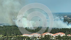 Aerial view of fire department helicopter extinguishing wildfire burning severely in North Port city, Florida. Emergency