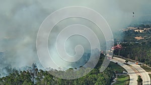 Aerial view of fire department helicopter and firetrucks extinguishing wildfire burning severely in Florida jungle woods