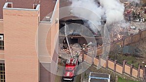 Aerial view of firefighters extinguishing fire in industrial or living area, near high office building after explosion