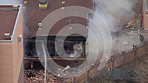 Aerial view of firefighters extinguishing fire in industrial or living area, near high office building after explosion