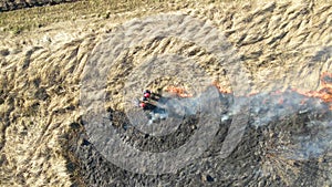 Aerial view of firemen extinguishing grassland field burning with red fire during dry season. Natural disaster and