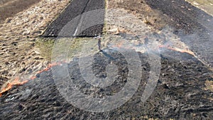 Aerial view of firemen extinguishing grassland field burning with red fire during dry season. Natural disaster and