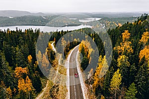 Aerial view of first snowy autumn color forest in the mountains and a road with car in Finland Lapland