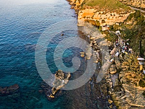 Aerial view of fishermen on the rocks, shacks and fishing posts on a cliff by the sea. Shelters and slums. Italian coast, Pizzo Ca