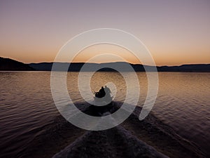 Aerial view of a fishermens on a speed motor boat fishing on a lake with beautiful sunrise