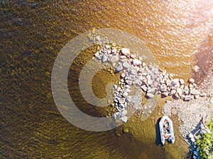 Aerial view of a fishing motor boat in the lake. Beautiful summer landscape with ships. Clear water with sandy and stone beach at